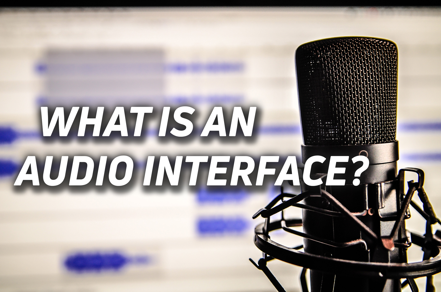 An image of a microphone in front of a computer, with overlaid text reading "what is an audio interface?"