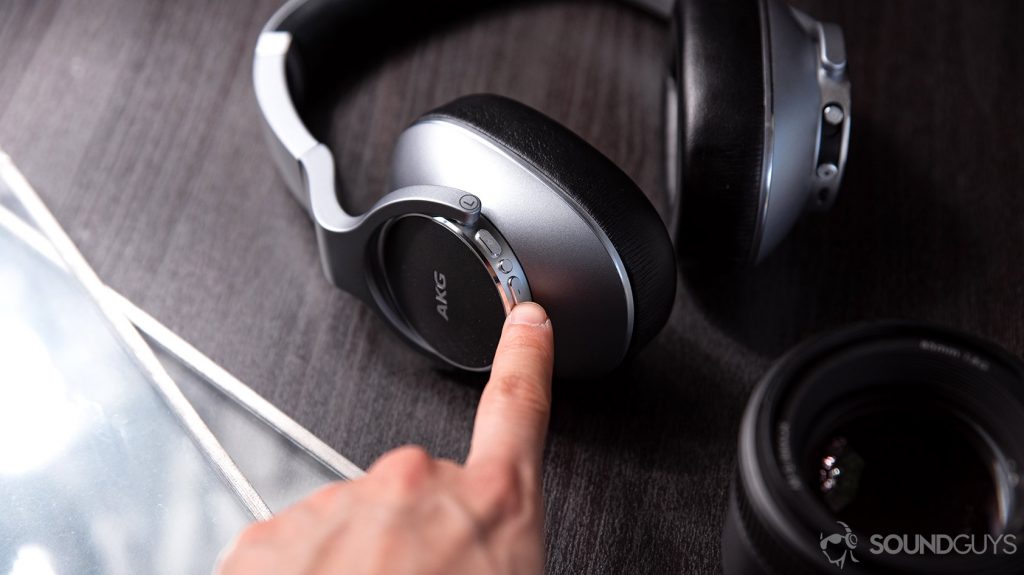 AKG N700NC: A hand reaching out for the volume controls on the left ear cup.