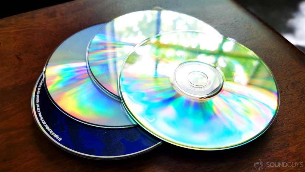 A photo of CDs on a wooden table.