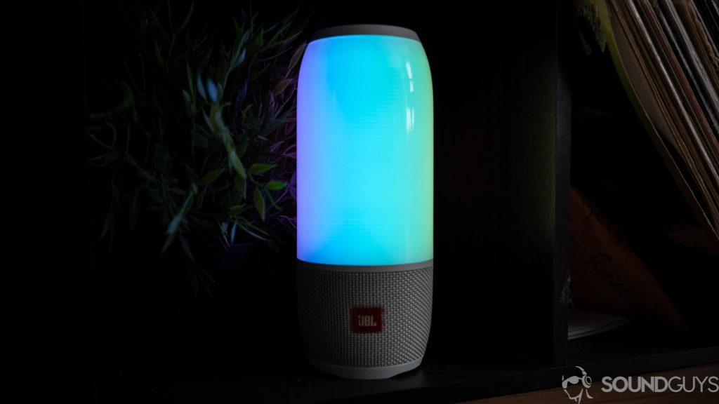 Shot of the JBL Pulse 3 in the dark in front of plants and old records. 