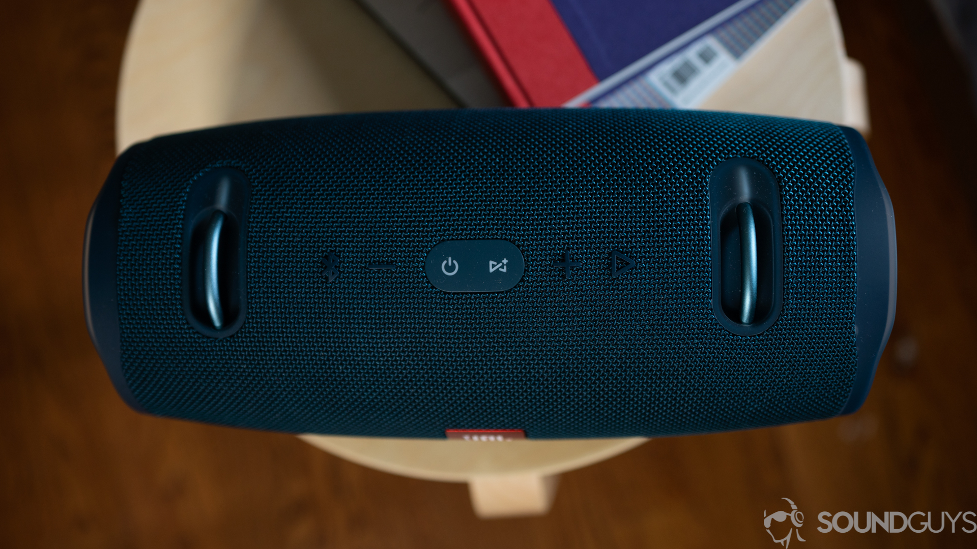 JBL Xtreme 2-2 Pictured are the playback buttons on top of the JBL Xtreme 2 speaker on a wooden stool with books.