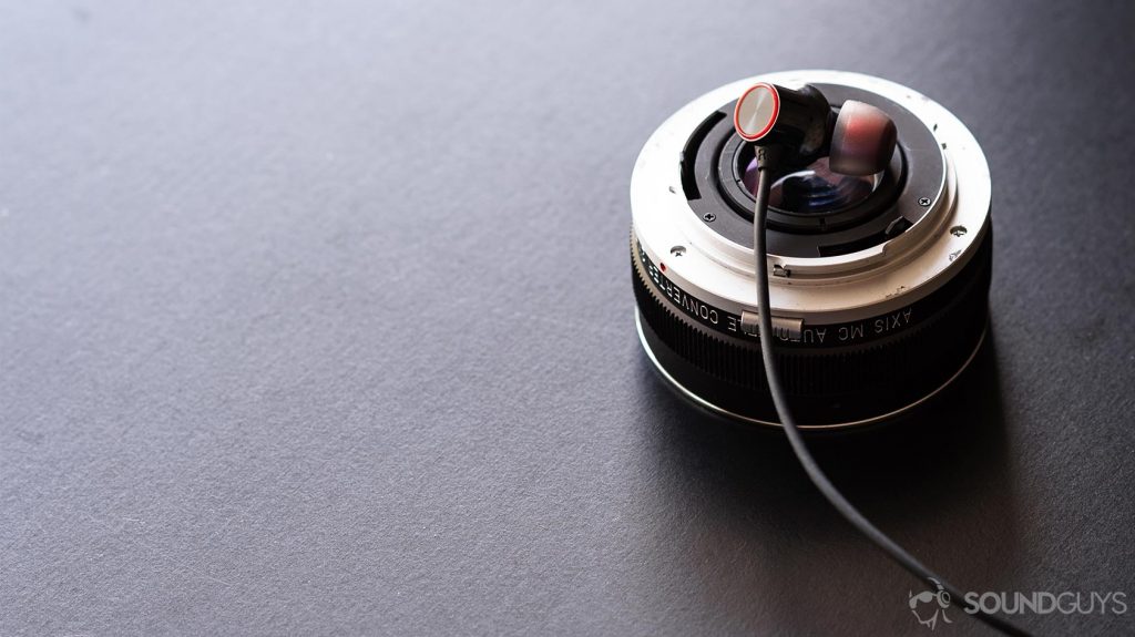 A picture of the OnePlus Bullets Wireless 2 earbud on a lens converter and black table.