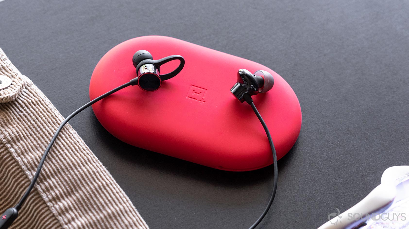 A picture of the OnePlus Bullets Wireless 2 with the old Bullets Wireless on the left and new on the right. They're sitting on the red carrying pouch.
