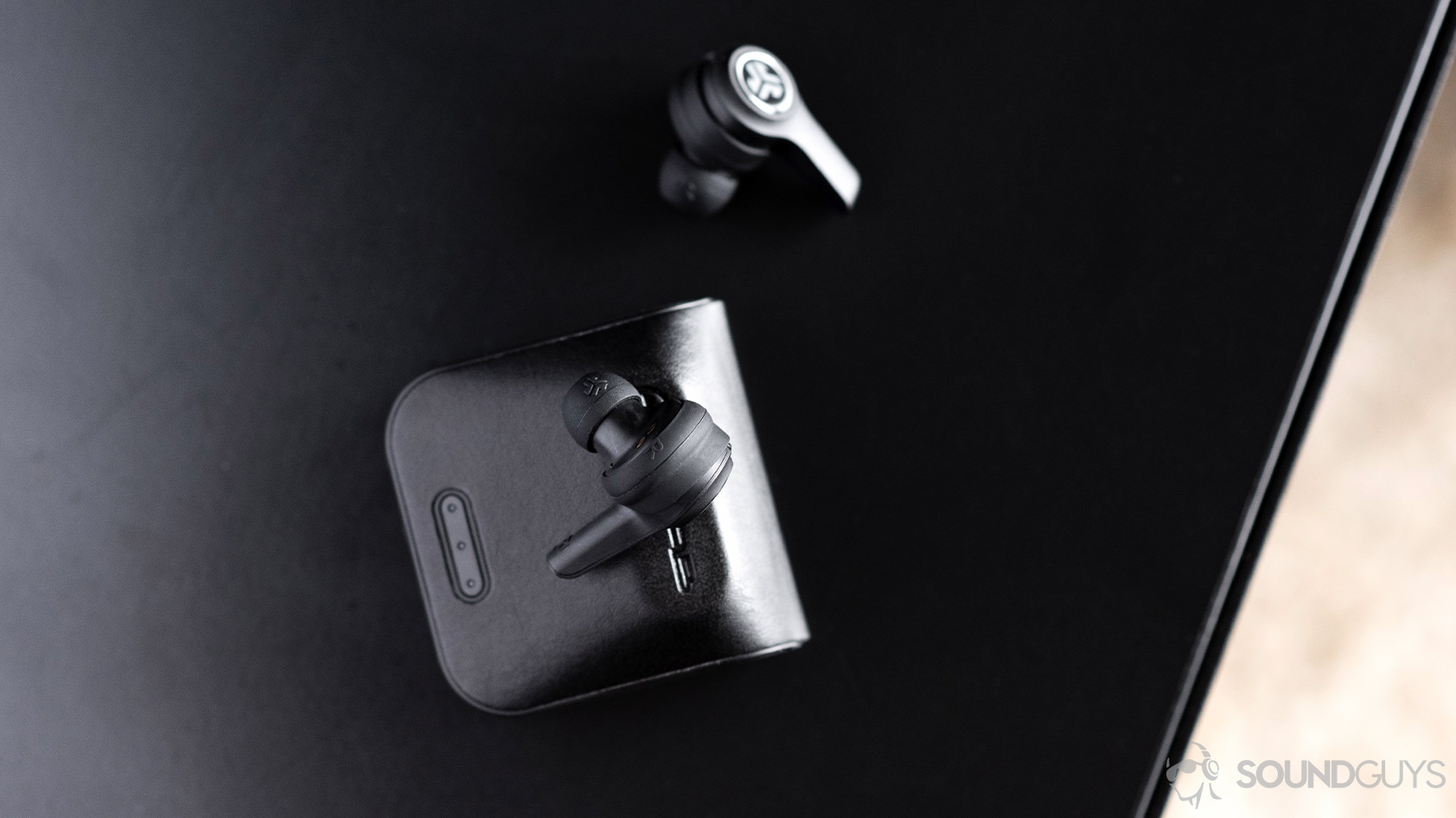 JLab_JBuds Air Executive-4_aerial earbuds case Aerial image of the JLab JBuds Air Executive. One earbud is atop the closed case and another is off to the side.