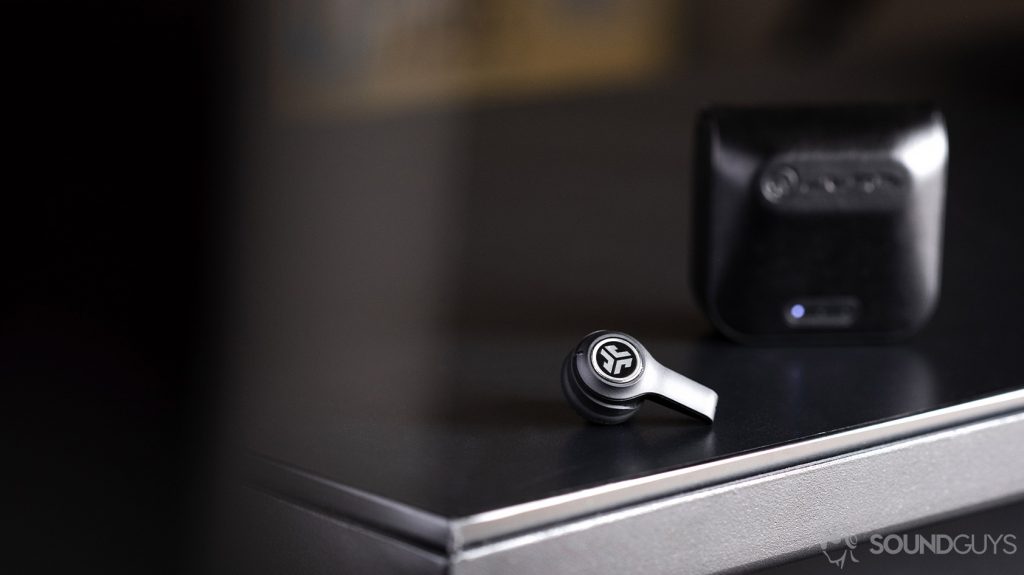 An image of one JLab JBuds Air Executive earbud outside of the case, which is standing vertically.