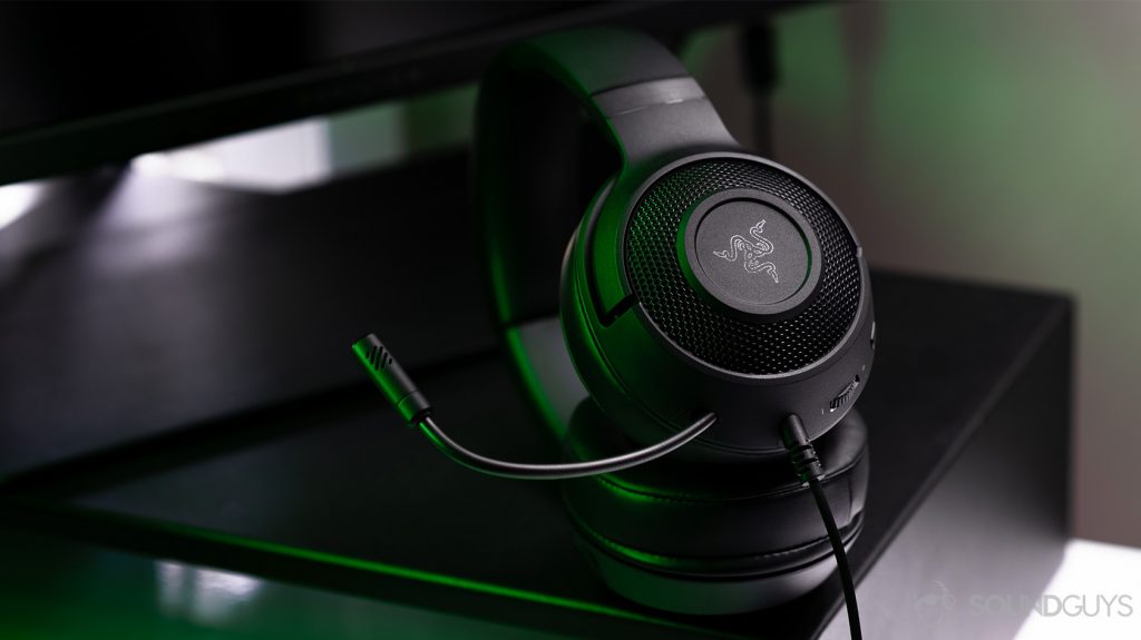 The headphones angled on a computer stand with the microphone bent slightly upward.