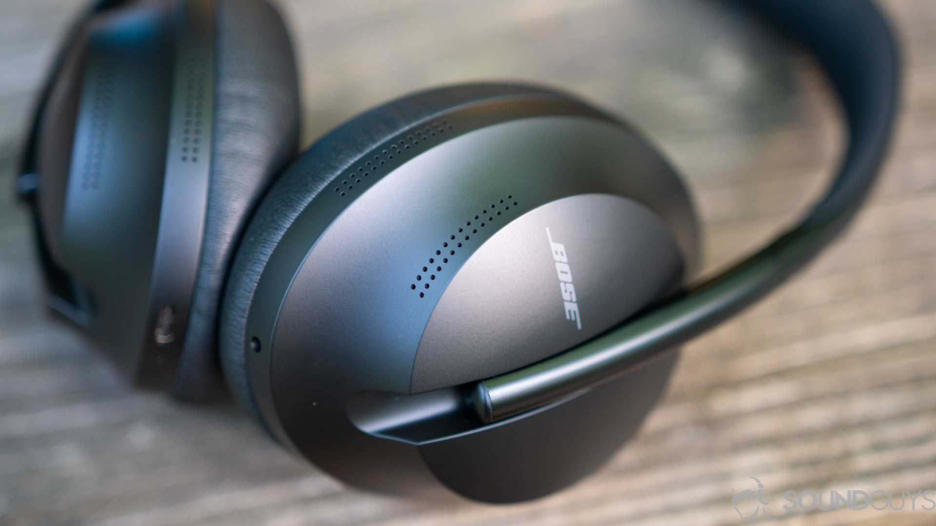 The Bose Noise Canceling Headphones 700 on a wooden surface with the Bose logo in focus.