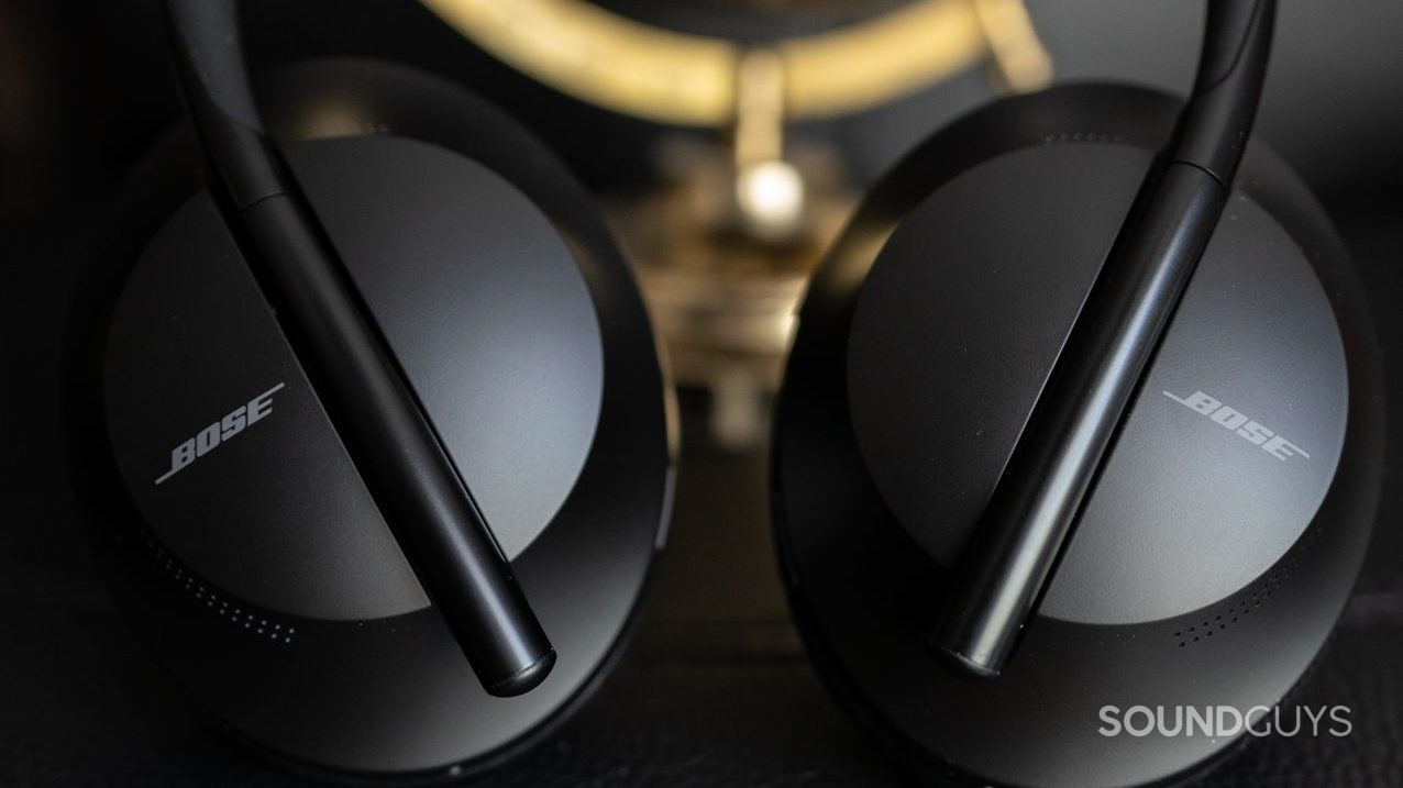 The Bose Noise Cancelling headphones 700 on a black surface resting against a globe.