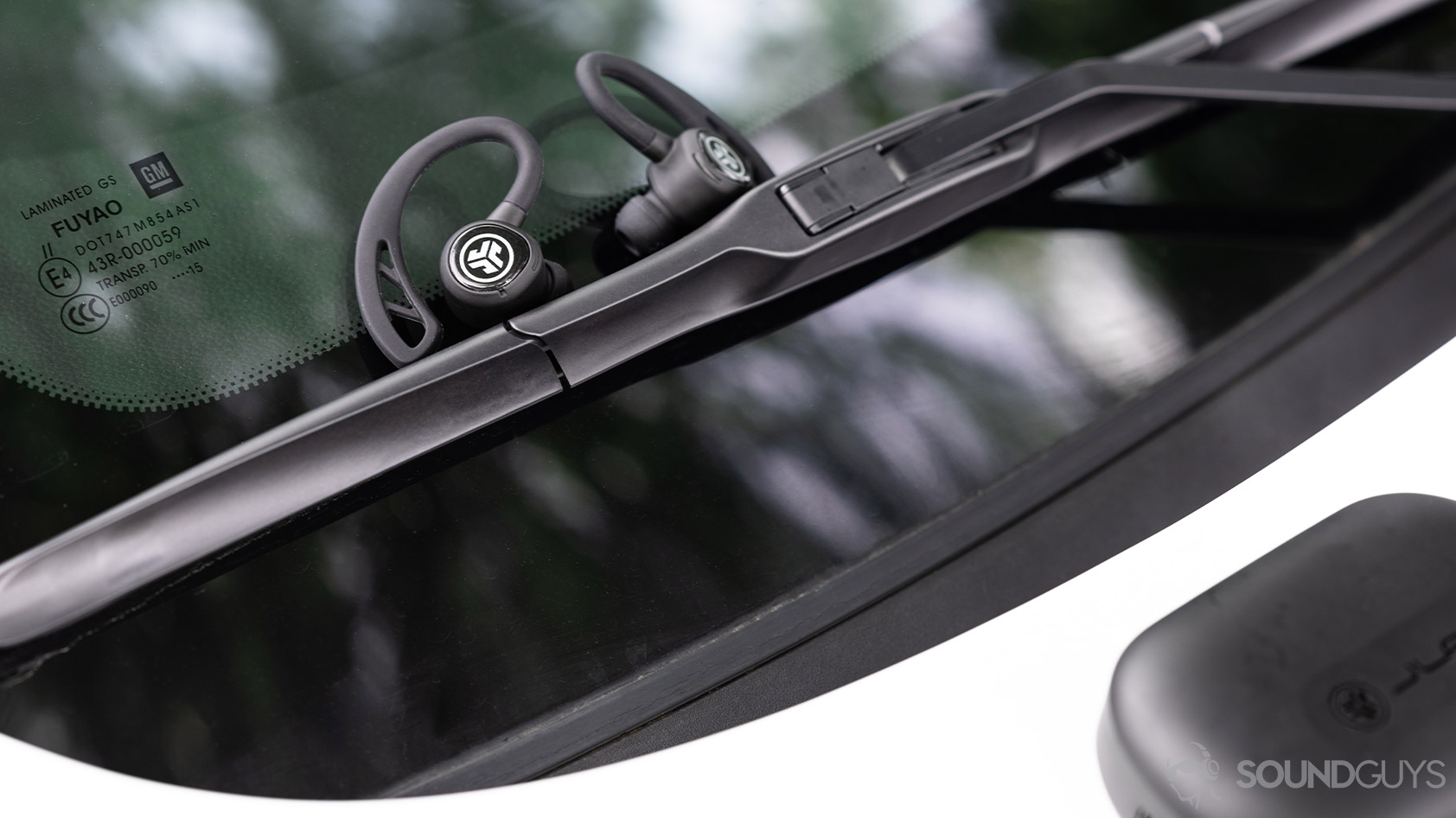 The JLab Epic Air Sport earbuds on a car's windshield wipers.