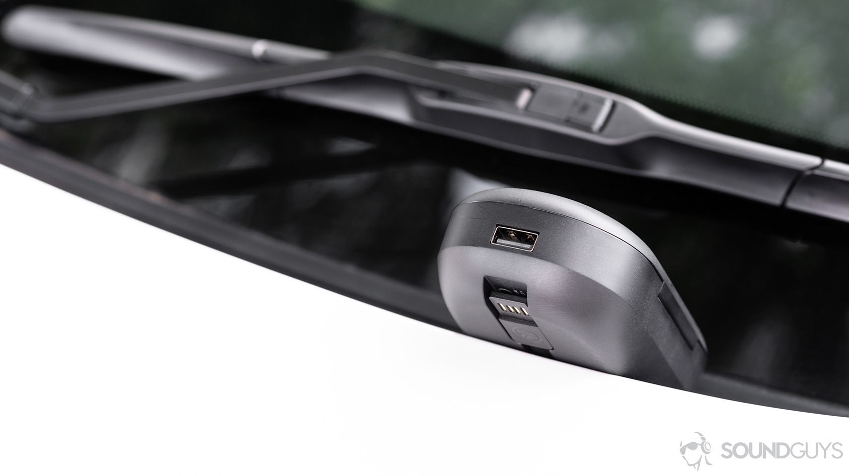 The USB-A input and USB cable visible on the JLab Epic Air Sport charging case, which is resting on a car windshield.