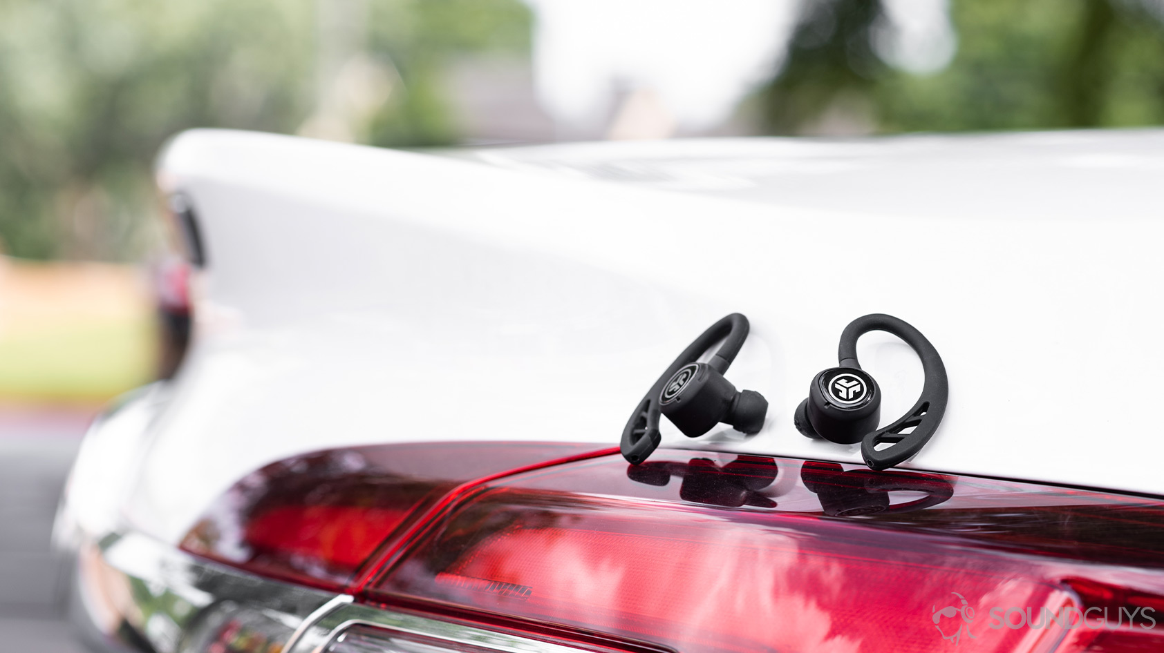The JLab Epic Air Sport earbuds on a Buick car tail light.