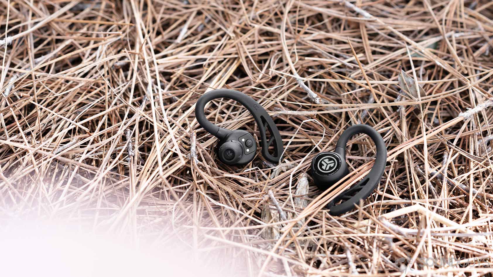 The JLab Epic Air Sport earbuds on a bed of straw.