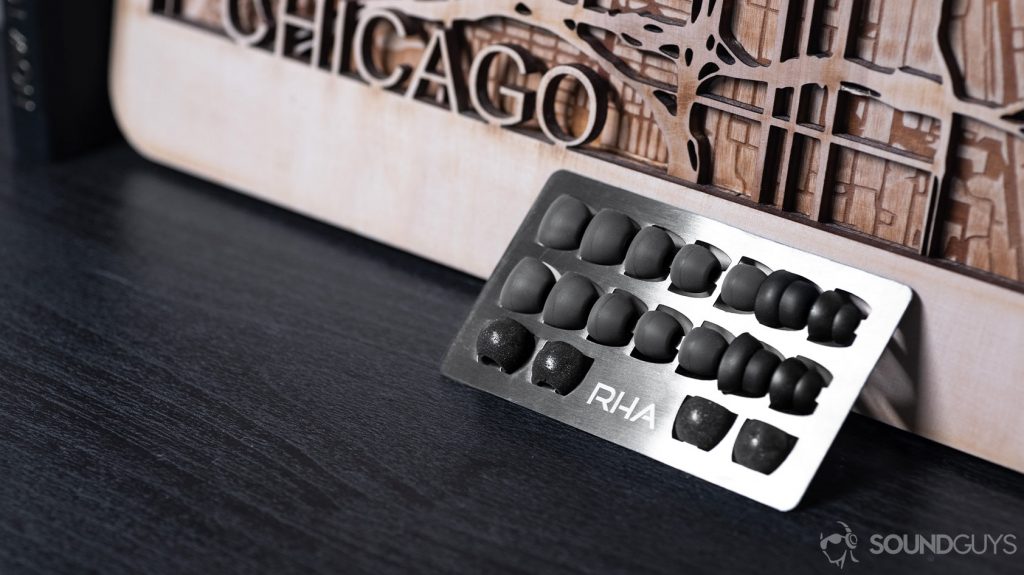 RHA T20 Wireless aluminum ear tip holder leaning against a laser cut wood piece.