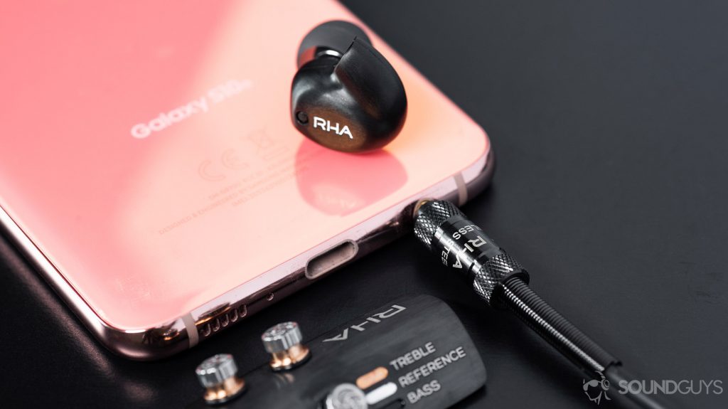 RHA T20 Wireless detachable earbud atop a Samsung Galaxy S10e with the filter holder on the bottom left part of the image.