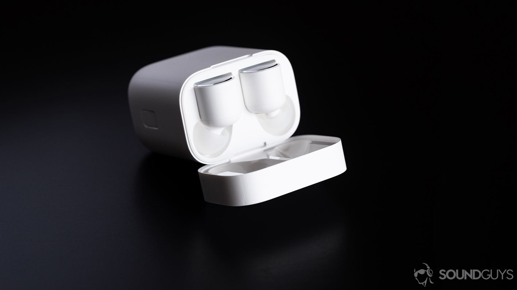 Xiaomi Mi True Wireless earbuds in the charging case which is open and resting on a black surface.