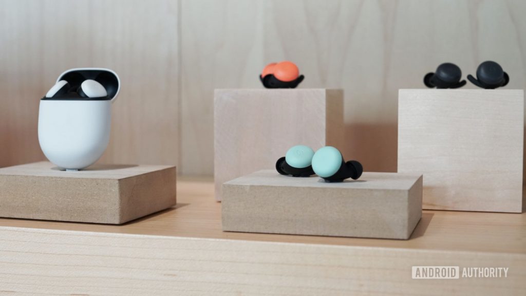 An image of the Google Pixel Buds in white, orange, light blue, and black all on a wood block display.