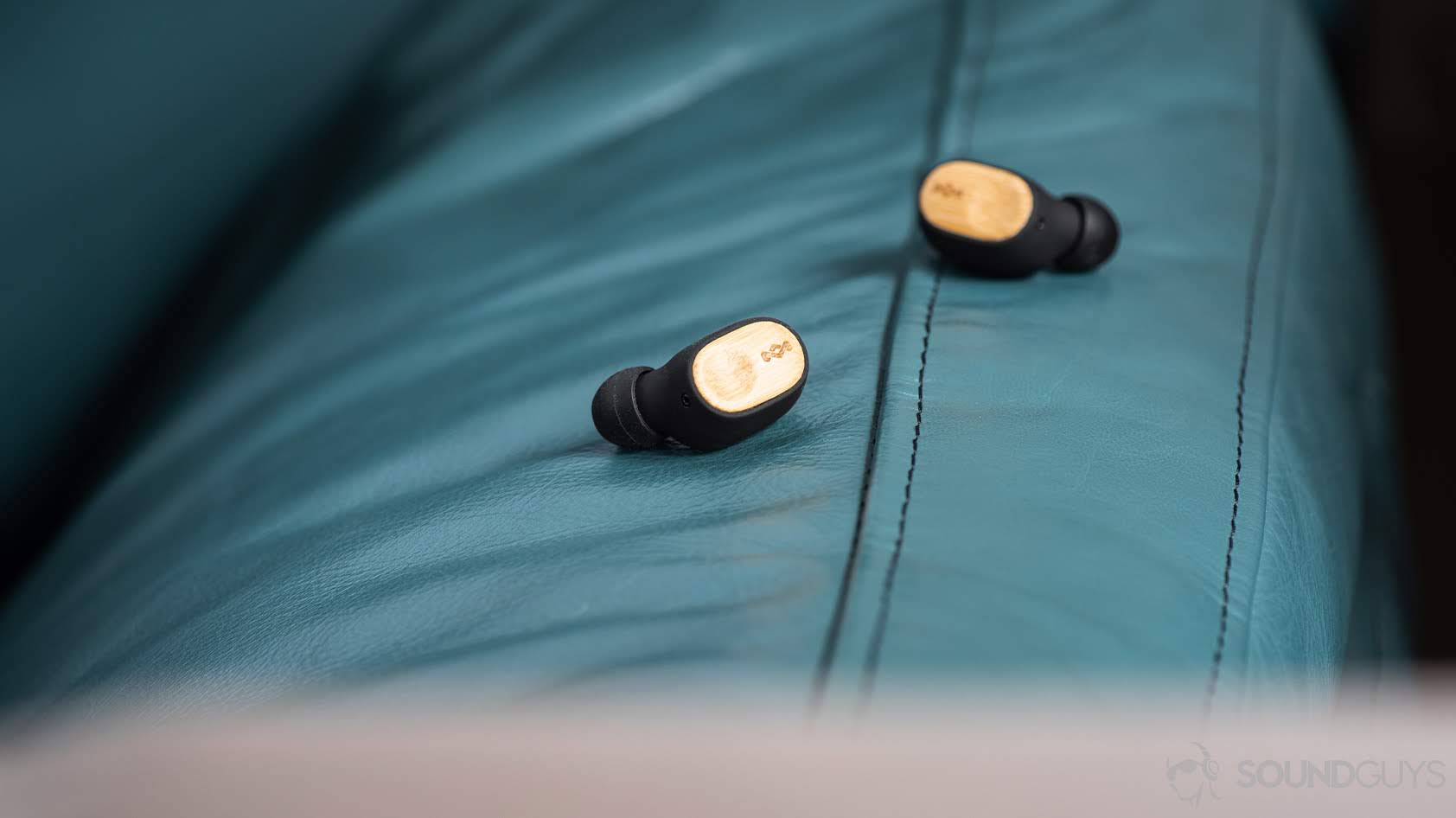 The House of Marley Liberate Air earbuds on a teal surface.
