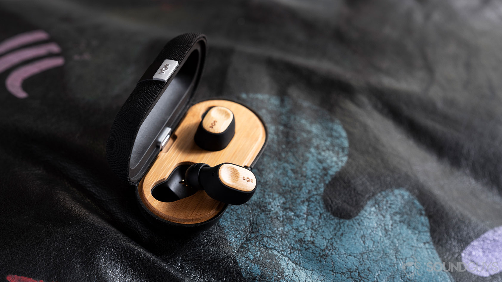 House of Marley Liberate Air true wireless earbuds with on earbud in the case and the other on top.