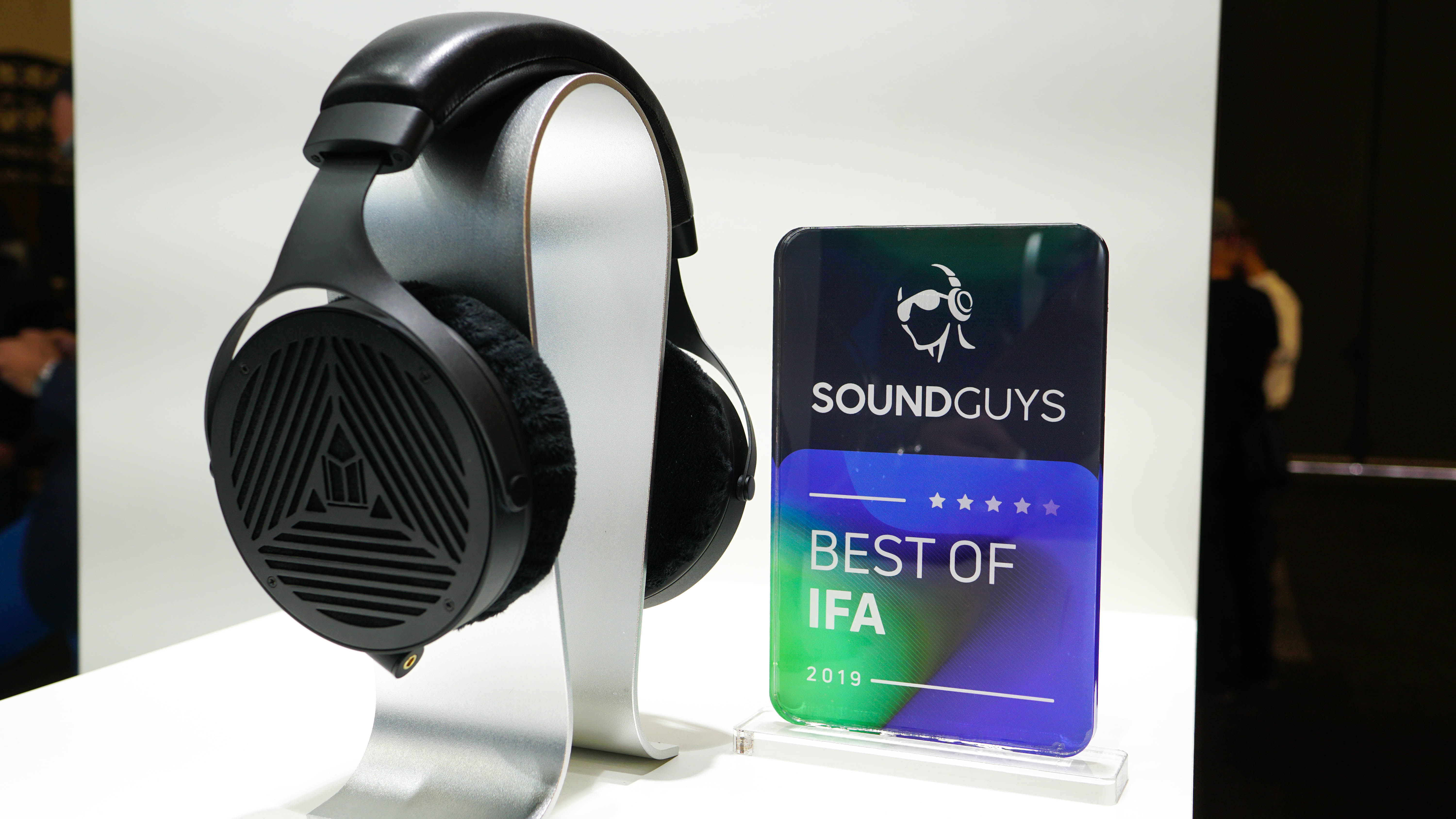 A photo of the Monoprice Monolith M1070 headphones on a stand next to the SoundGuys Best of IFA award.