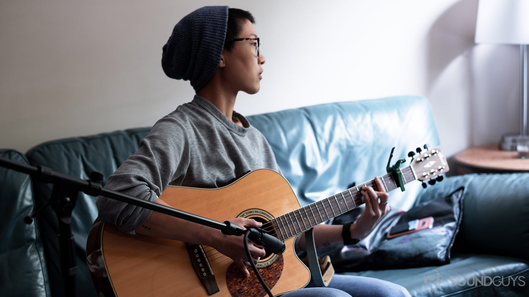 A picture of woman playing guitar and recording it with the Shure SM57 XLR mic.