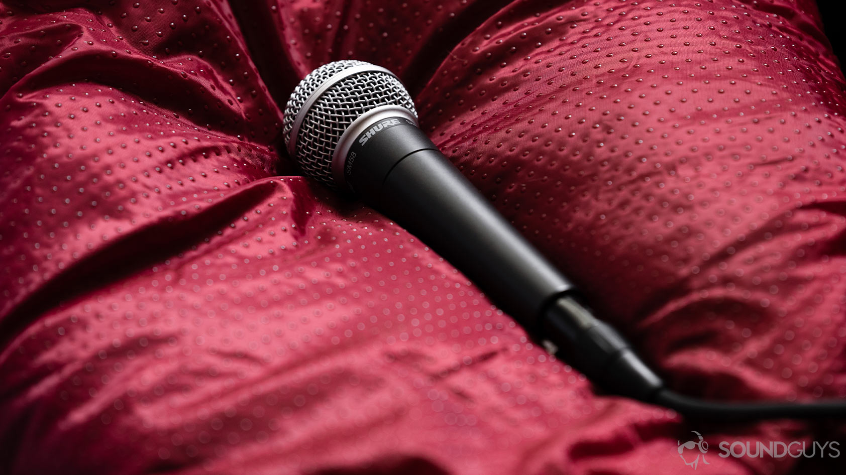 Shure SM58 dynamic microphone on red surface.