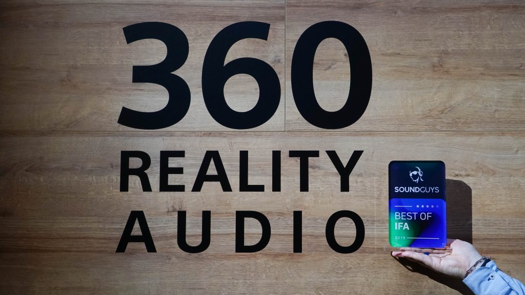 A photo of someone holding up a SoundGuys Best of IFA award nexxt to the Sony 360 Reality Audio logo.