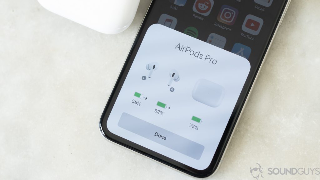Apple iPhone on marble table with battery life of the AirPods Pro and its charging case displayed on the screen. 