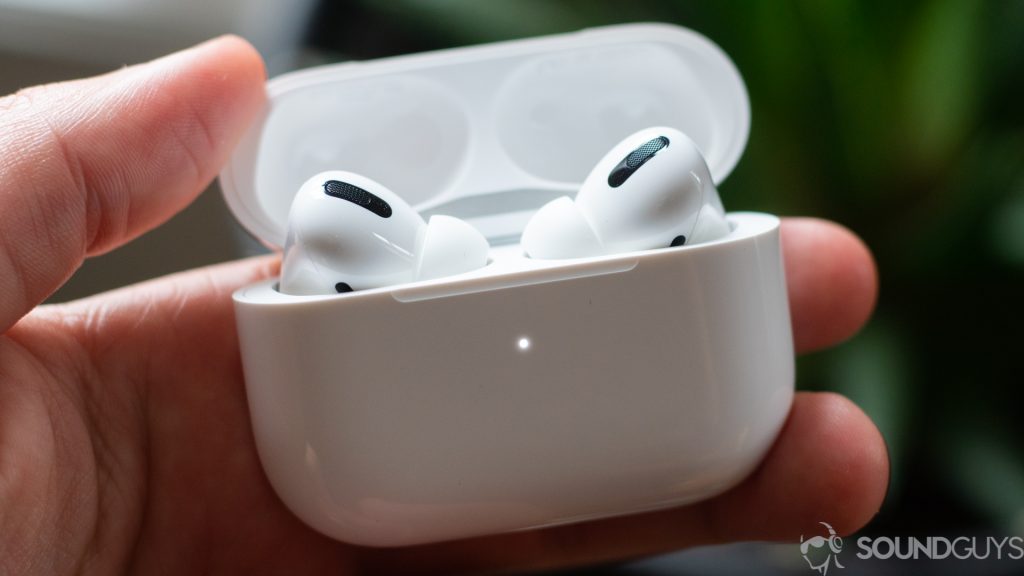 A picture of the Apple AirPods Pro true wireless earbuds in the case being held by a man's left heand.