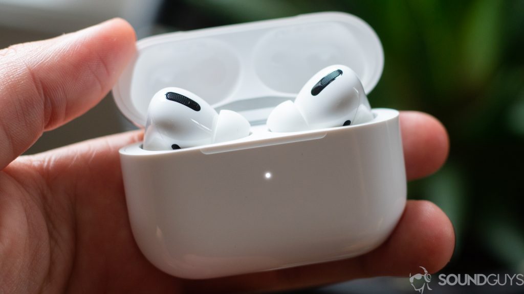 Une image d'un vrai casque sans fil Apple AirPods Pro dans le boîtier tenu par la main gauche d'un homme.