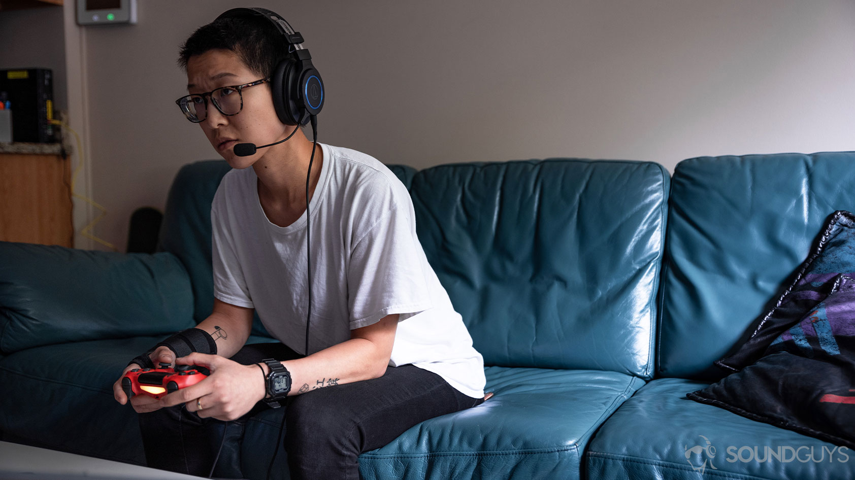 A woman playing on a PlayStation 4 with the Audio-Technica ATH-G1 headset plugged directly into the controller.