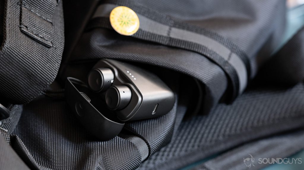 The Cambridge Audio Melomania 1 in the charging case which is open and laying against a backpack side pocket.