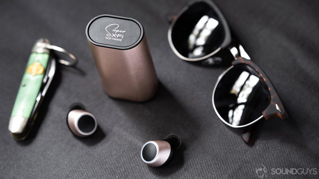 An image of the Creative Outlier Air charging case with the Super X-Fi logo in focus, surrounded by sunglasses and an army knife.