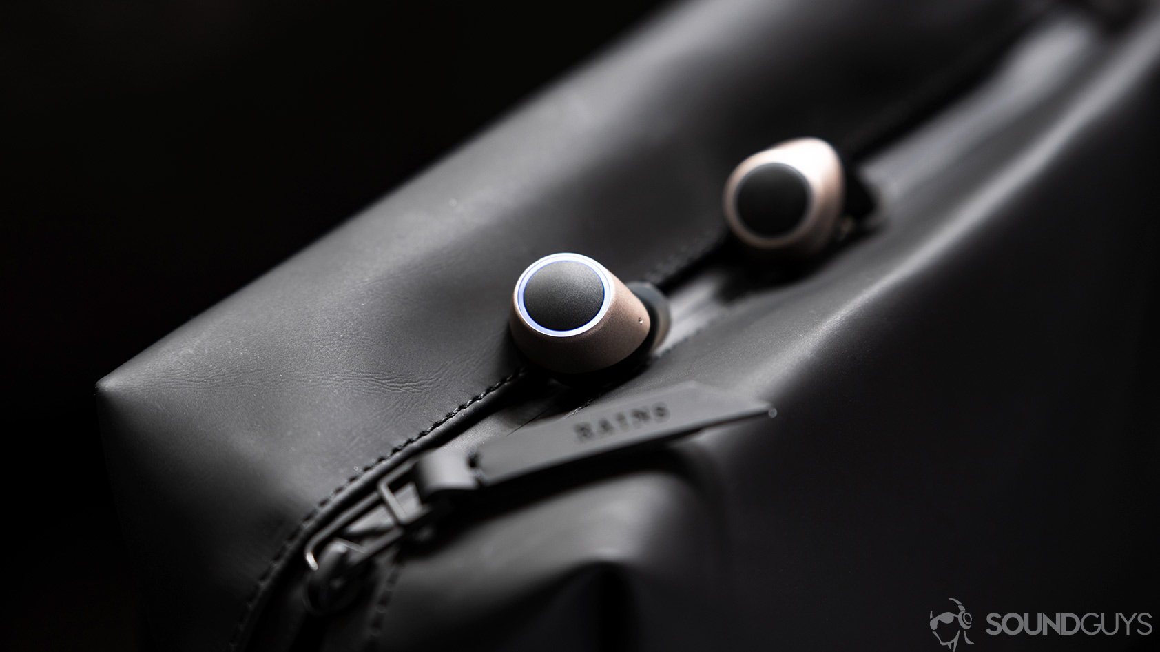 The Creative Outlier Air earbuds in champagne gold on a black waterproof bag.
