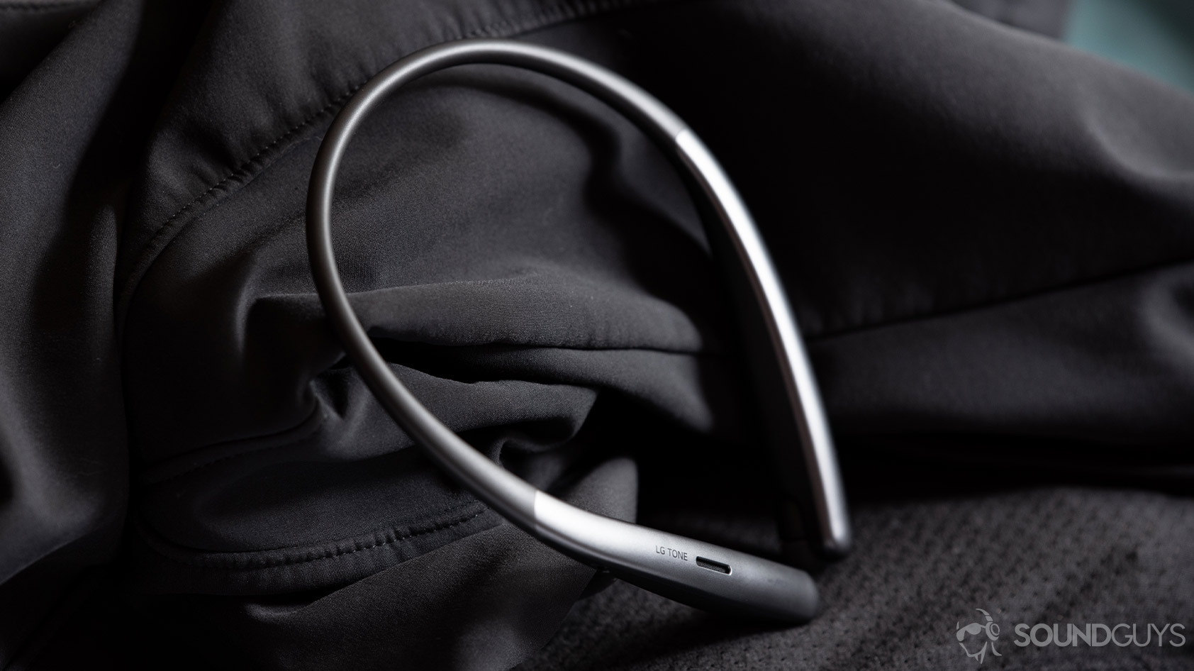 Angled, static image of the LG Tone Style SL6s wireless neckband earbuds on a black, textured surface.