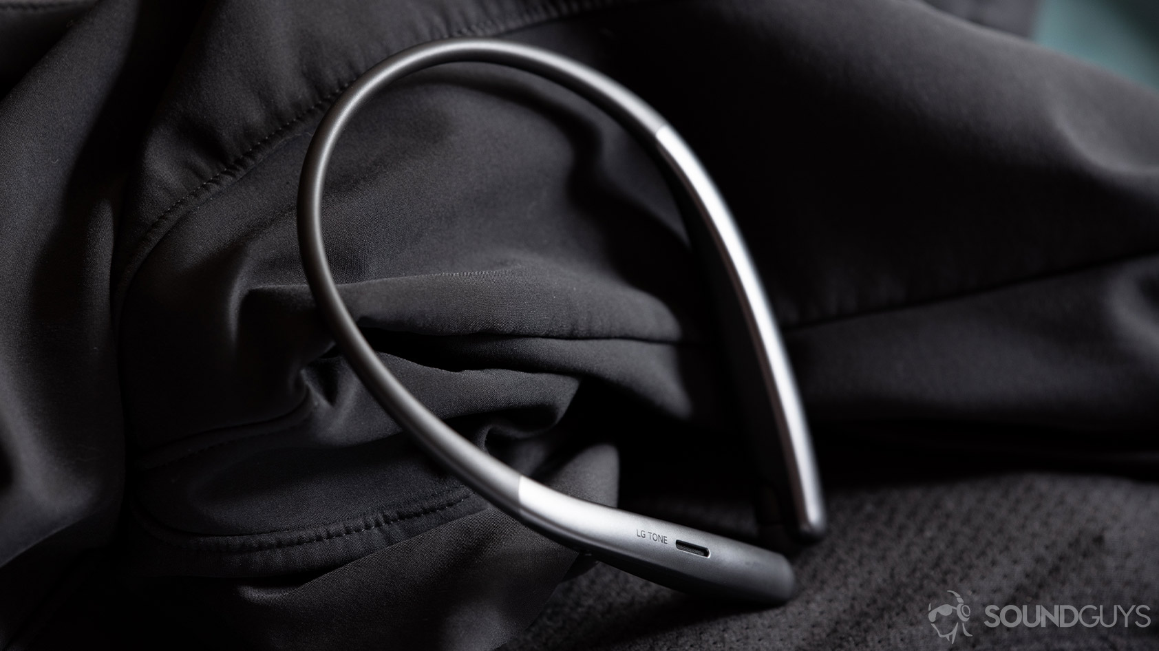 LG Tone Style SL6s wireless neckband earbuds angled black surfaces Angled, static image of the LG Tone Style SL6s wireless neckband earbuds on a black, textured surface.