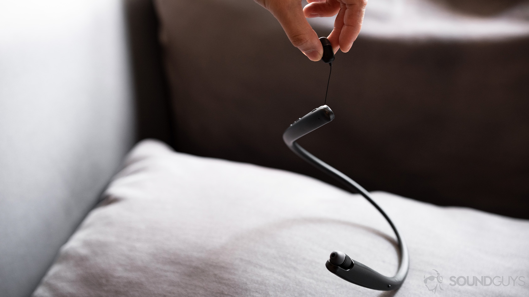 The LG Tone Style SL6s earbuds being suspended to show the thinness of the cable.