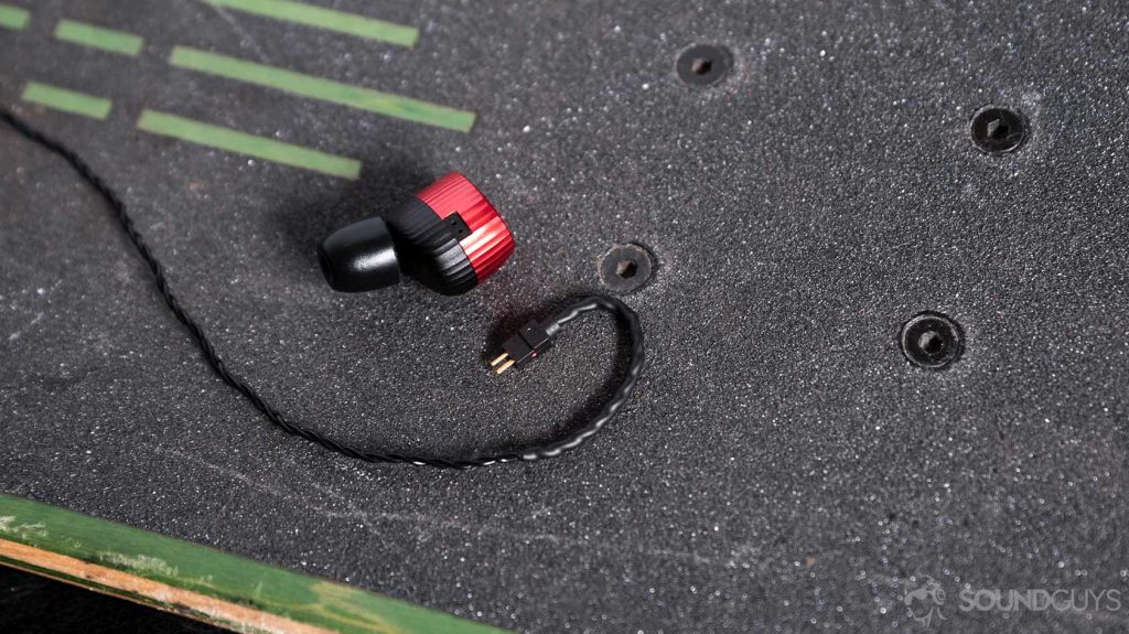 An aerial photo of the Massdrop x Noble Kaiser 10 Universal earbuds connector disconnected from the housings on a skateboard.