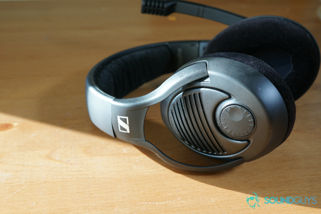 The Sennheiser PC37X lies on a wooden table, half covered in direct sunlight, which illuminates the headset's volume dial.