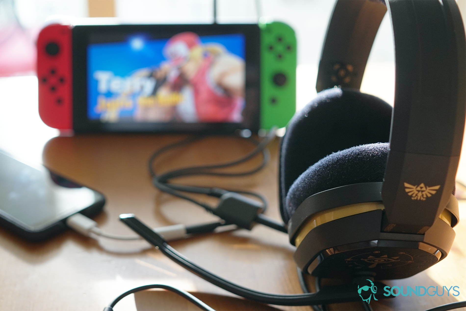 The Legend of Zelda Astro A10 sitting front of a Google Pixel 3 and a Nintendo Switch running Super Smash Bros. Ultimate, and all three are connected with the included splitter cord.