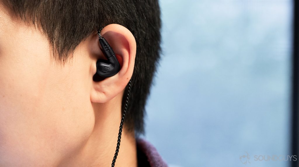 A photo of the Frequency response chart of the Massdrop x MEE audio Pinnacle PX earbuds worn by a woman.