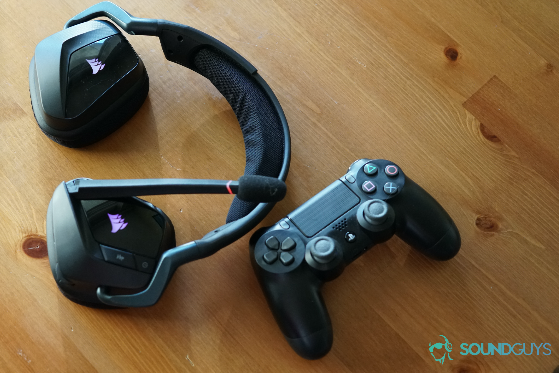 Situs headset gaming nirkabel rgb rgb rgb nirkabel di atas meja kayu di sebelah pengontrol ganda untuk Sony PlayStation 4