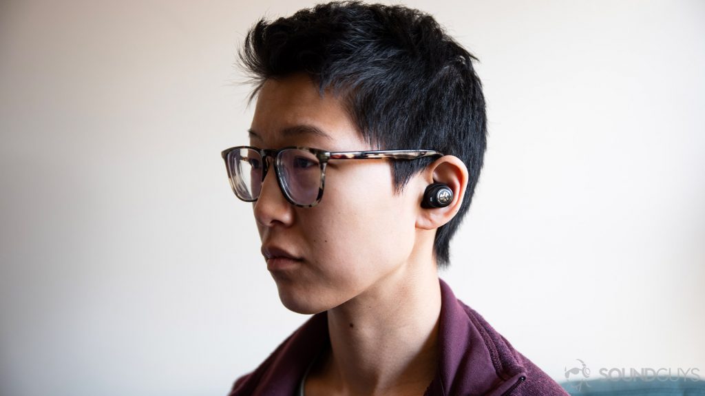 A picture of the JLab JBuds Air Icon, which serve as cheap Apple AirPods Pro alternatives, worn by a woman looking to the left of the frame.