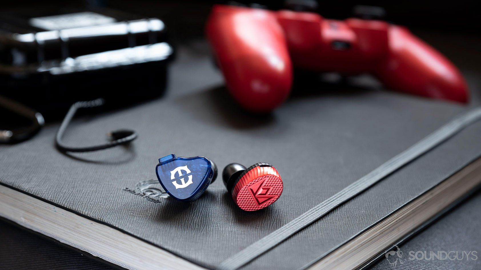 Massdrop x Empire Ears Zeus-Noble Audio Kaiser 10 comparison A photo of the Massdrop x Empire Ears Zeus and Massdrop x Noble Audio Kaiser 10 in-ear monitors next to each other with a PS4 controller in the background.