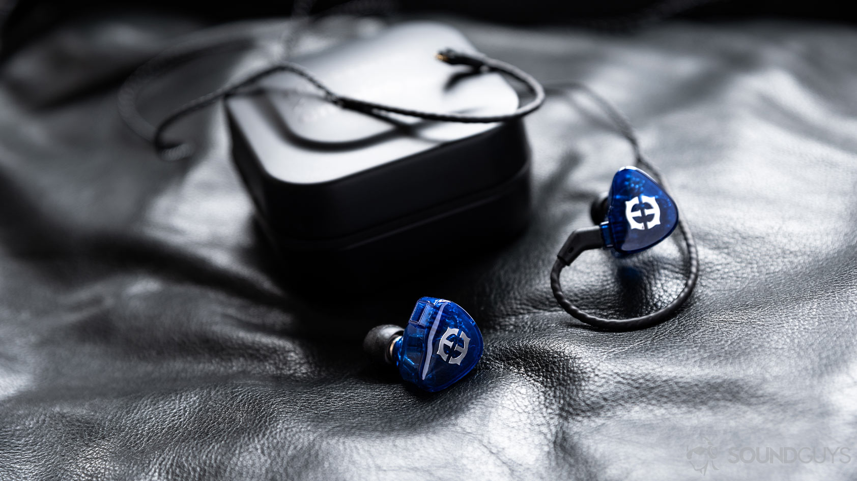 A photo of the Massdrop x Empire Ears Zeus earbuds in blue in front of the included carrying case.