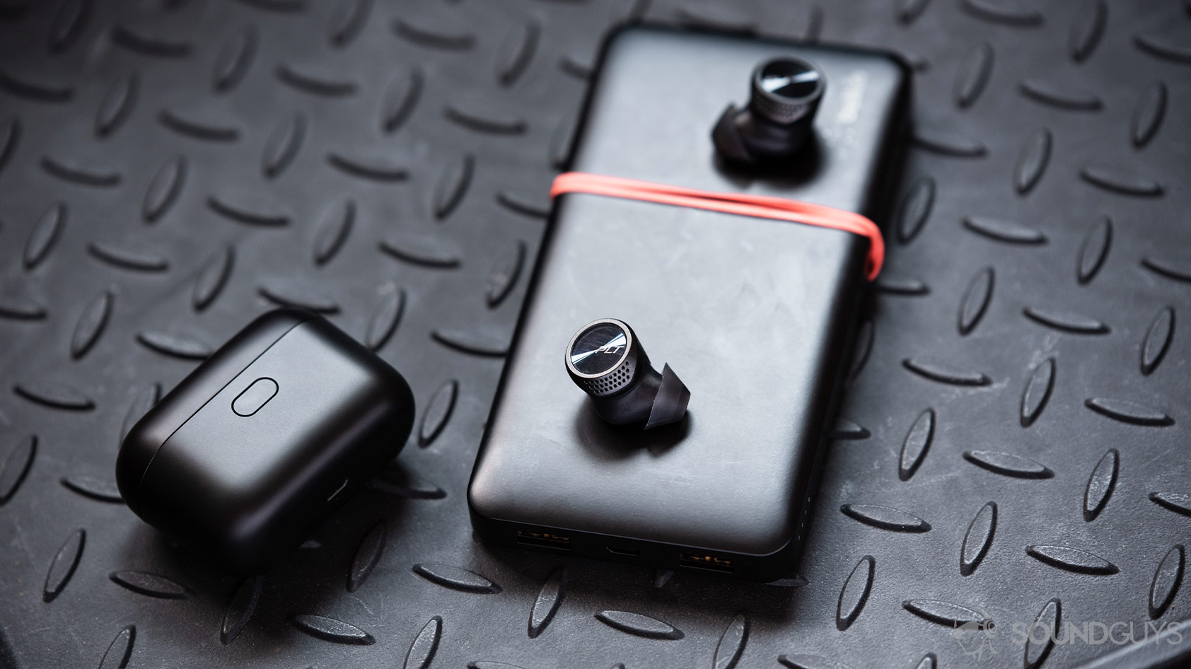 A picture of the Plantronics BackBeat Pro 5100 true wireless earbuds outside of the case (closed) atop a Belkin battery pack.