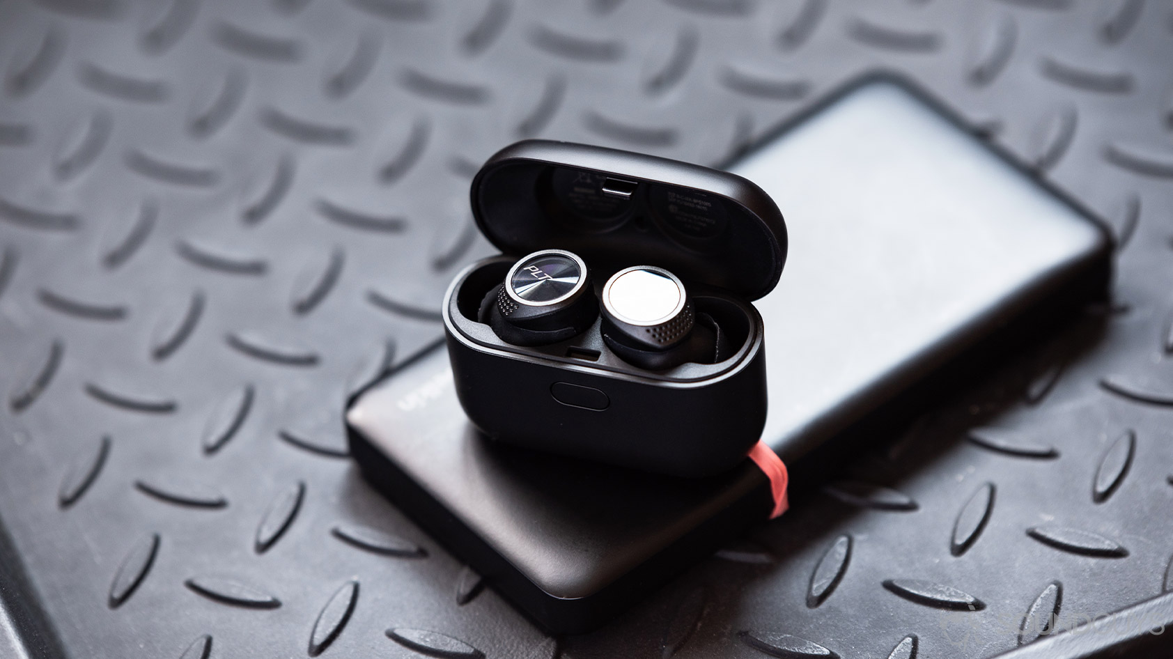 A picture of the Plantronics BackBeat Pro 5100 true wireless earbuds in the provided case, both are black.