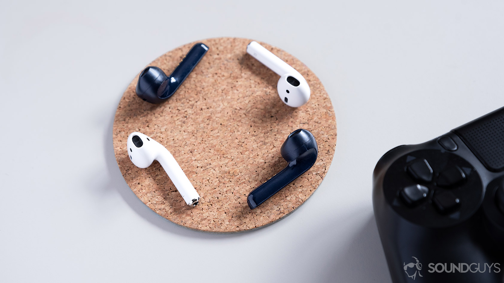 Mobvoi TicPods 2 Pro true wireless earbuds compared to the Apple AirPods on a cork coaster.
