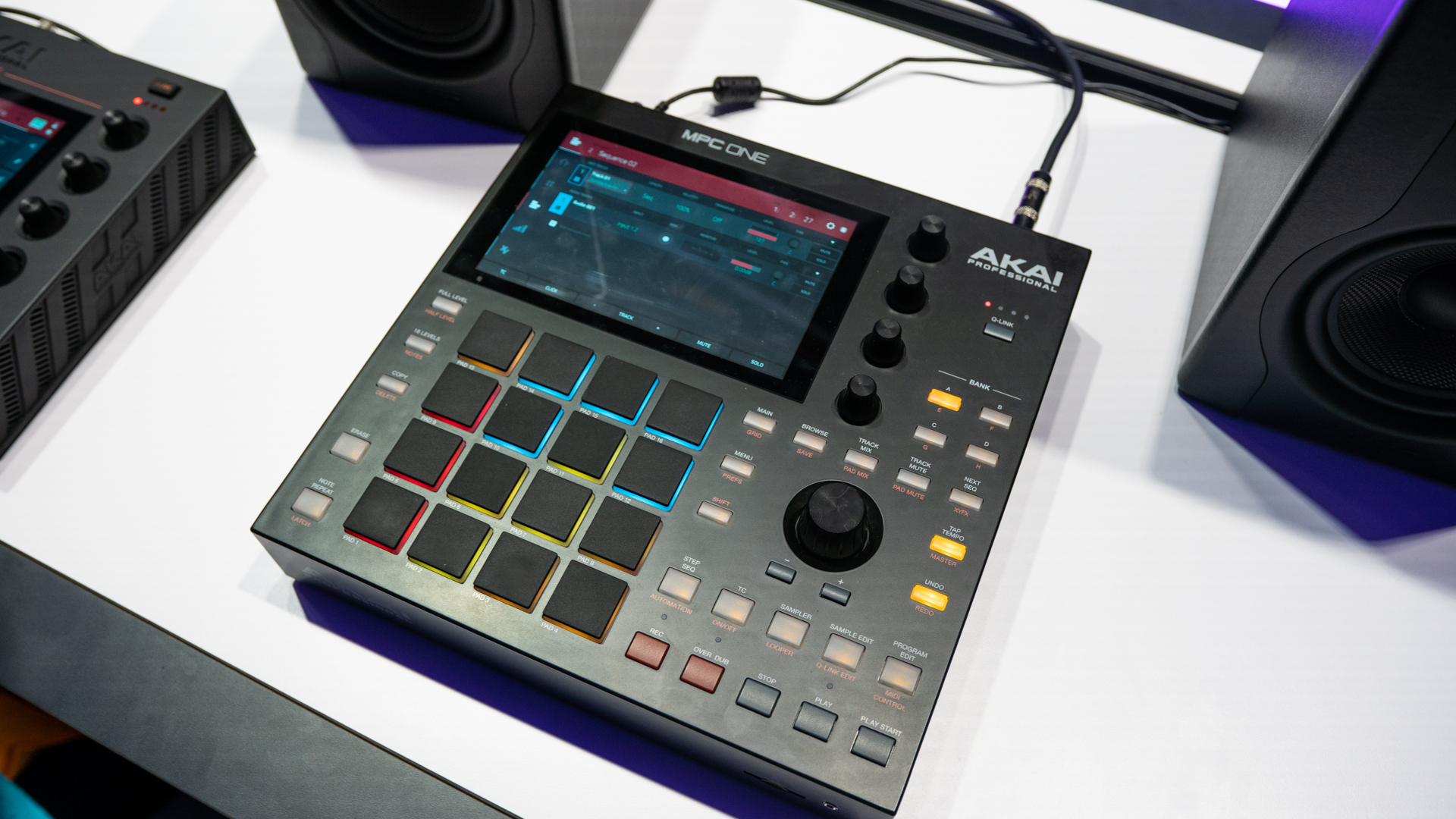 The MPC One pictured from the top with the screen on and colorful pads. 