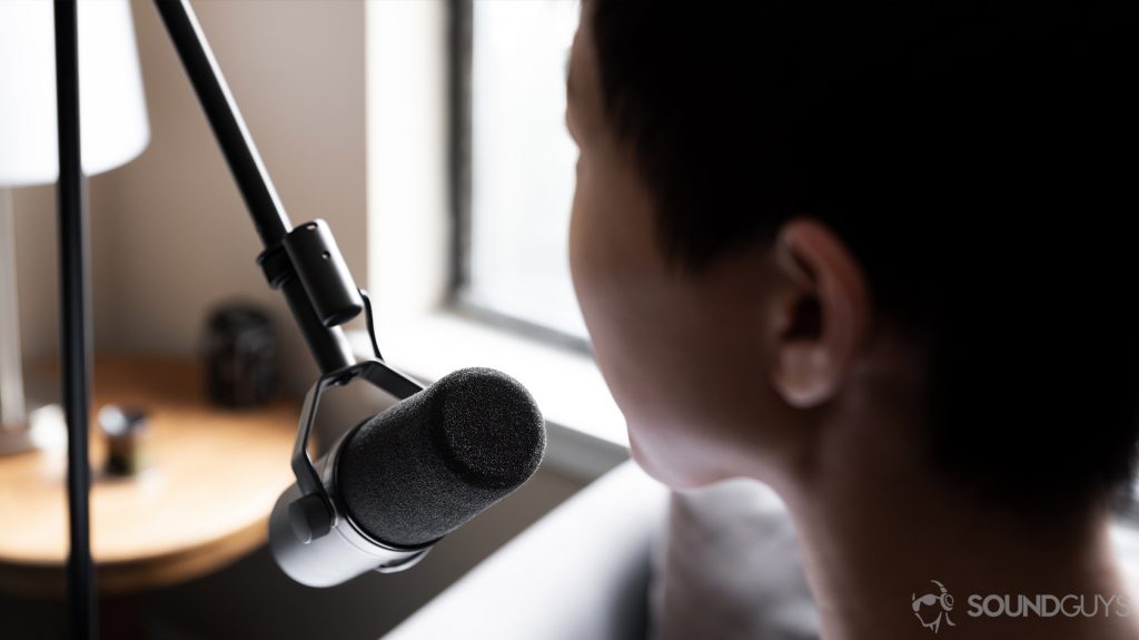 A photo of the Shure SM7B dynamic microphone facing a woman speaking into it, the high-end choice to podcast at home.