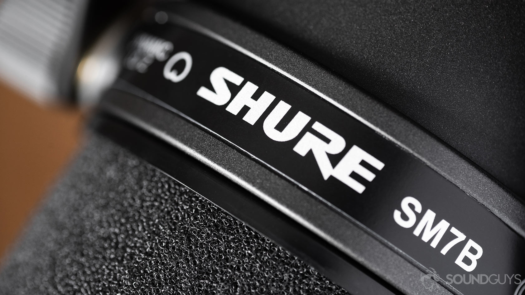 A macro photo of the Shure SM7B dynamic microphone Shure logo and cardioid icon.